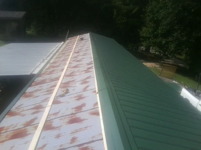 Old rusted panels beside newly installed green metal roofing — Wind Damage Roof Repair by Roofing Brothers in Mc Sherrystown
