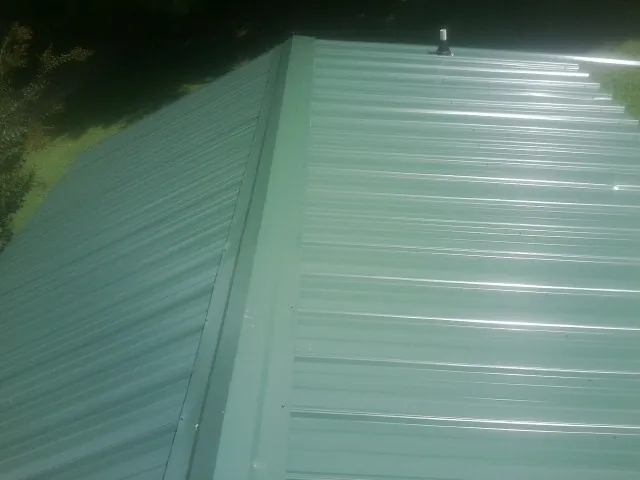 New green metal panels meeting at the ridge of a roof — Flat Roof Repair work by our crew in Mc Sherrystown