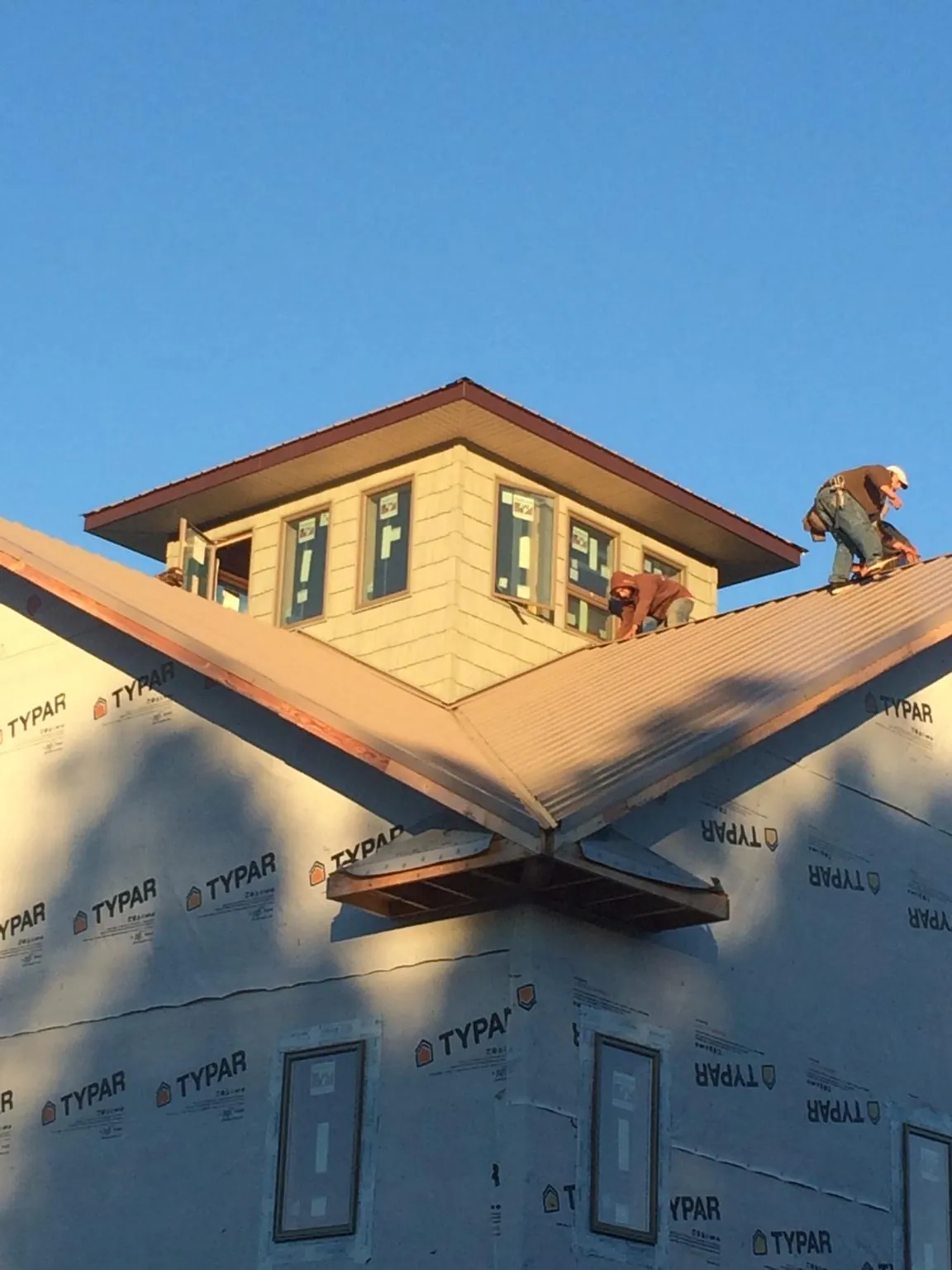 Roofers working around a rooftop cupola on a new metal roof at sunset — Roof Waterproofing in Mc Sherrystown by Roofing Brothers